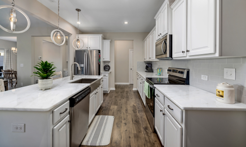 A fully stocked kitchen with white cabinets with black hardware.